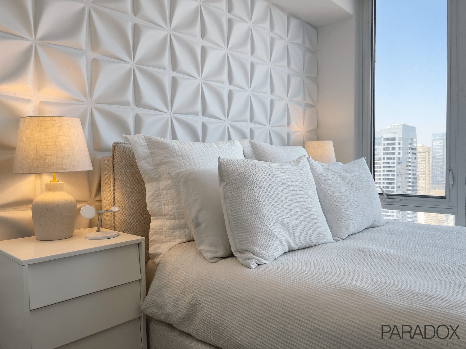 Monochromatic bedroom in a downtown Toronto condo with a custom upholstered headboard and layered textures