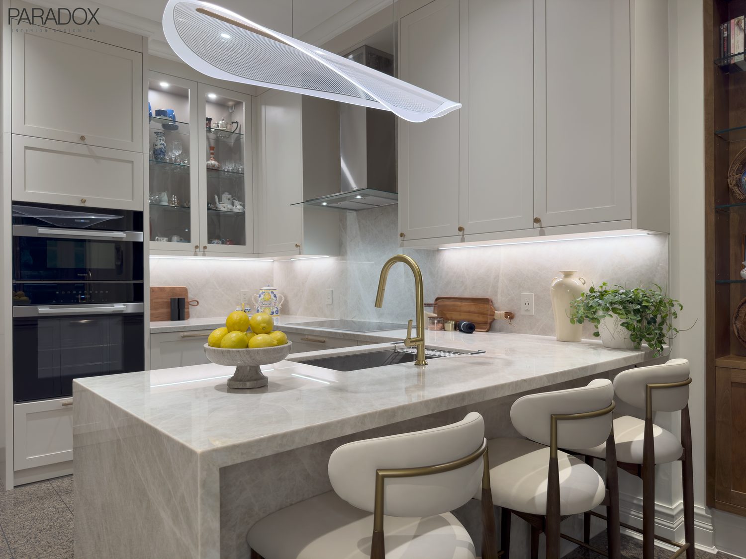 Renovated Bridle Path kitchen in Toronto with white custom cabinetry and Taj Mahal quartzite counters and backsplash